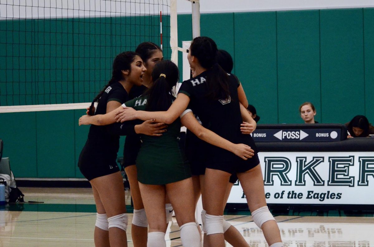 Members of the girls junior varsity team huddle to congratulate outside hitter Ashley Zhou (9) after she scores an ace. The Eagles struggled in the second set but made a comeback with strong hits and passes.