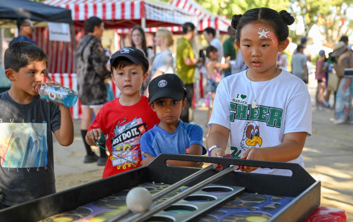 An attendee balances a ball between two rods while playing Space Miner in the Quad. Students and parents enjoyed various activities including carnival games, face painting and foosball.