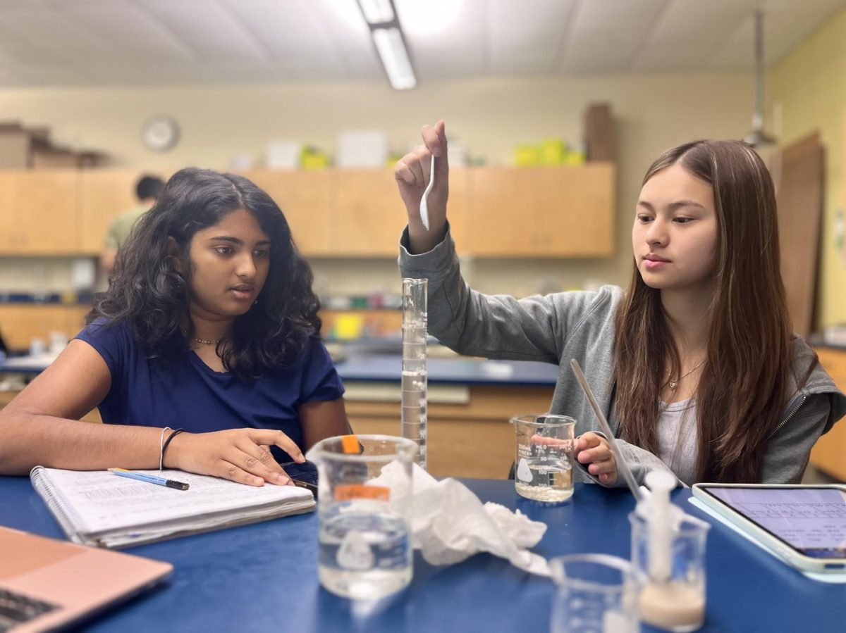 AP Biology students Savitha Satish (11) and Sophia Bagley (11) conduct the Catalase Lab. Students grouped together in pairs, with one person dropping the yeast spheres into the solution and the other person timing the reaction.