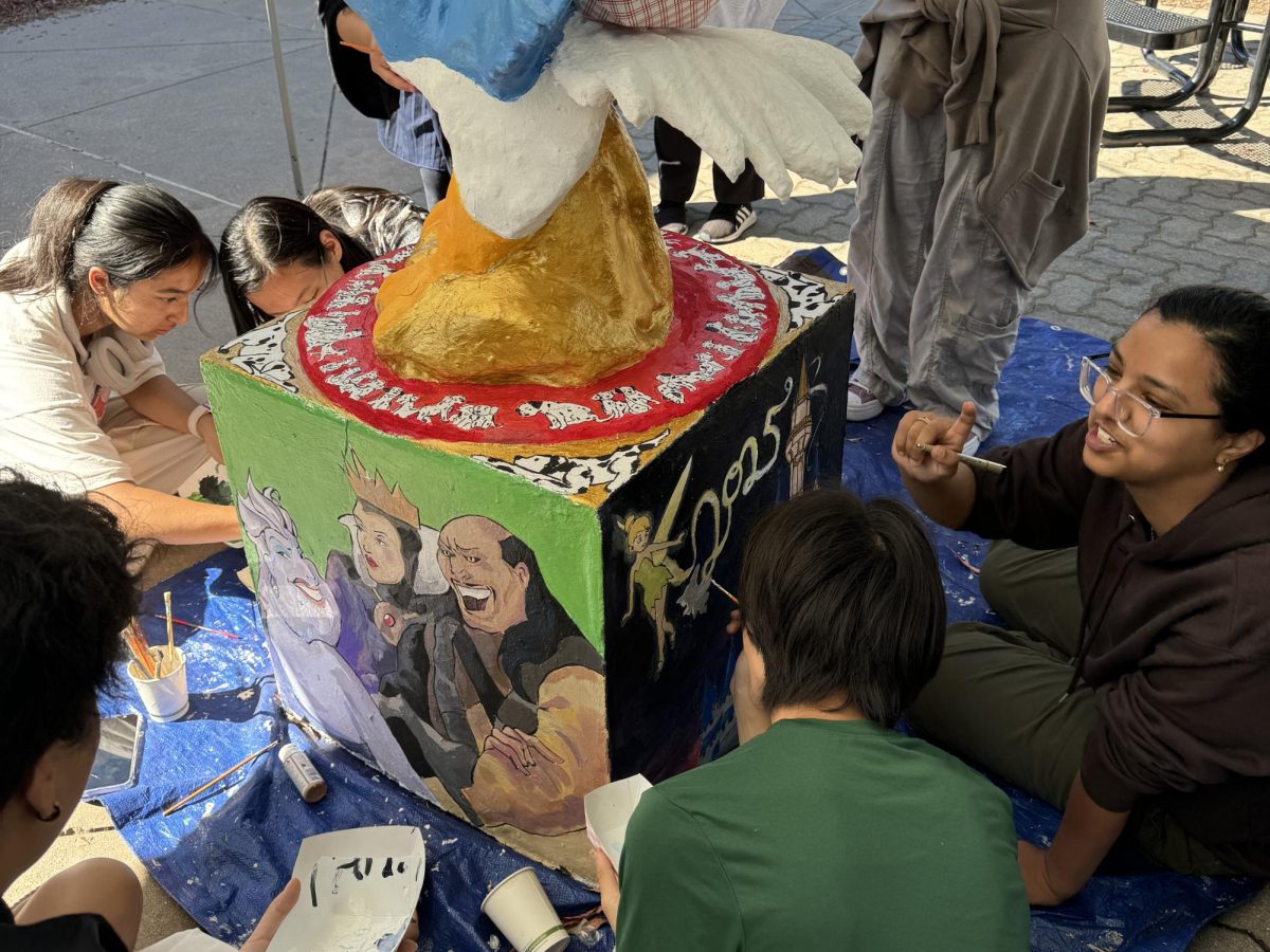 Seniors add finishing touches to their Disney-themed eagle on Sep. 26. With solid-colored backgrounds of pink, green and black, the sides feature Ariel and Snow White, Ursula and the Evil Queen and Tinker Bell flying over the Disney castle.