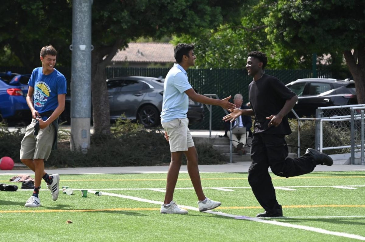 Sophomore Babila Mfonfu high fives junior Vivek Yalla as he runs to home base. The kickball event allowed students to make new connections with others in an uplifting and lighthearted environment.