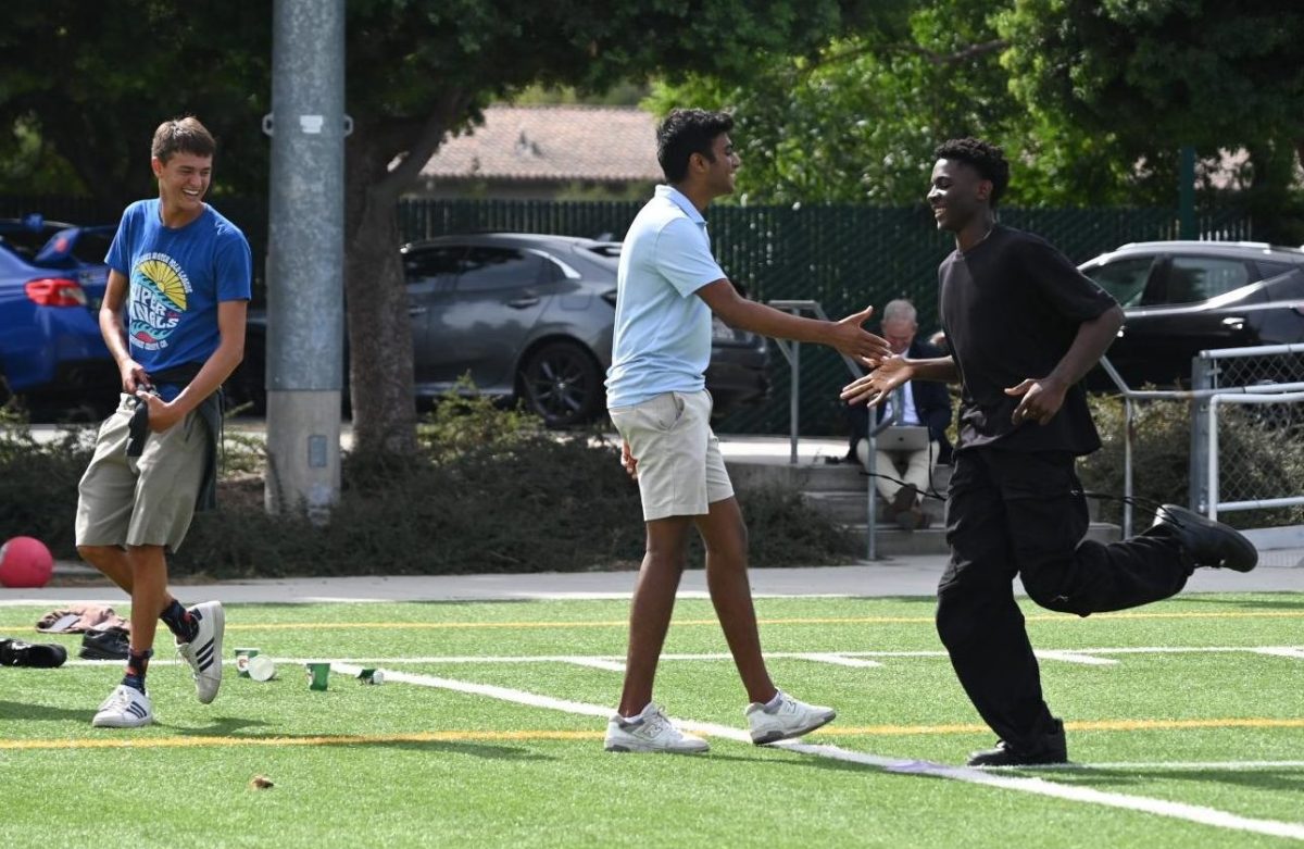 Sophomore Babila Mfonfu high fives junior Vivek Yalla as he runs to home base. The kickball event allowed students to make new connections with others in an uplifting and lighthearted environment.