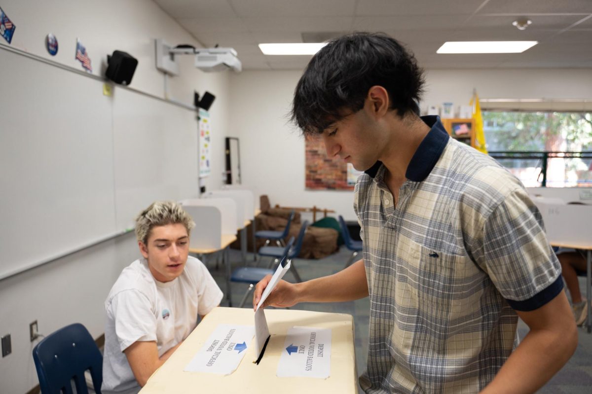 Senior Rishi Lalwani enters his ballot in the mock election. AP U.S. Government students took shifts manning the polling booths during their class period.