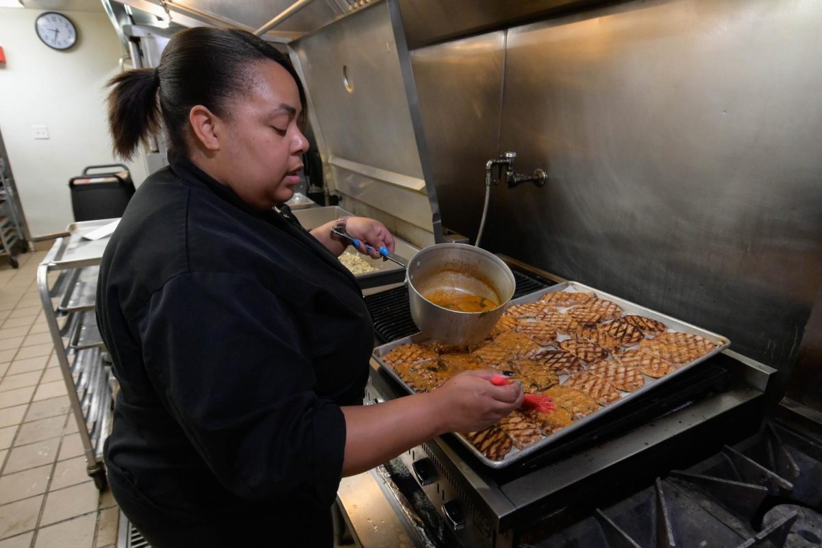 Kitchen Manager Raelynn Baldwin glazes some grilled pork before lunch. She gets here around 6 a.m.