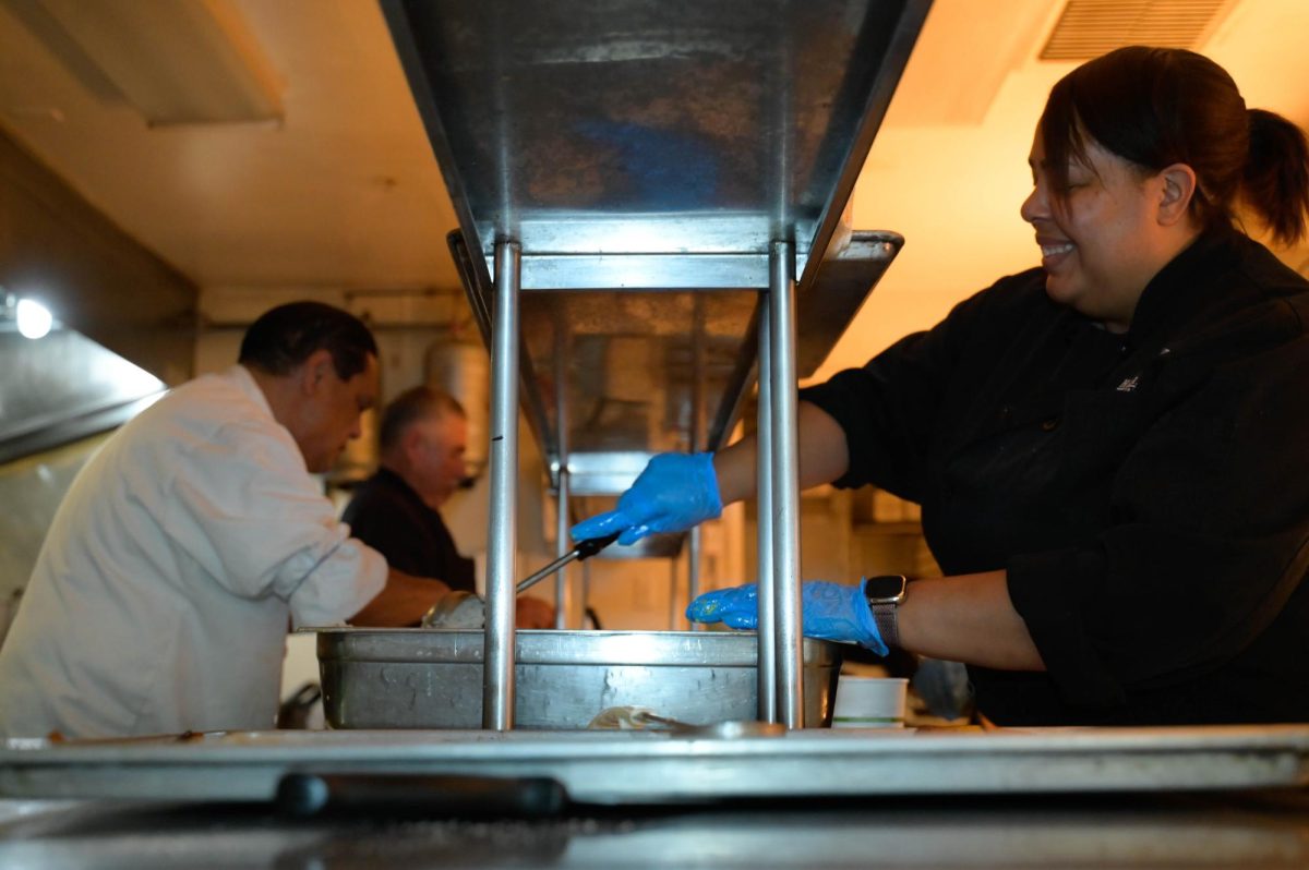 Baldwin scoops rice during lunch. The kitchen focuses mainly on assembling dishes during service, with preparation done beforehand. 