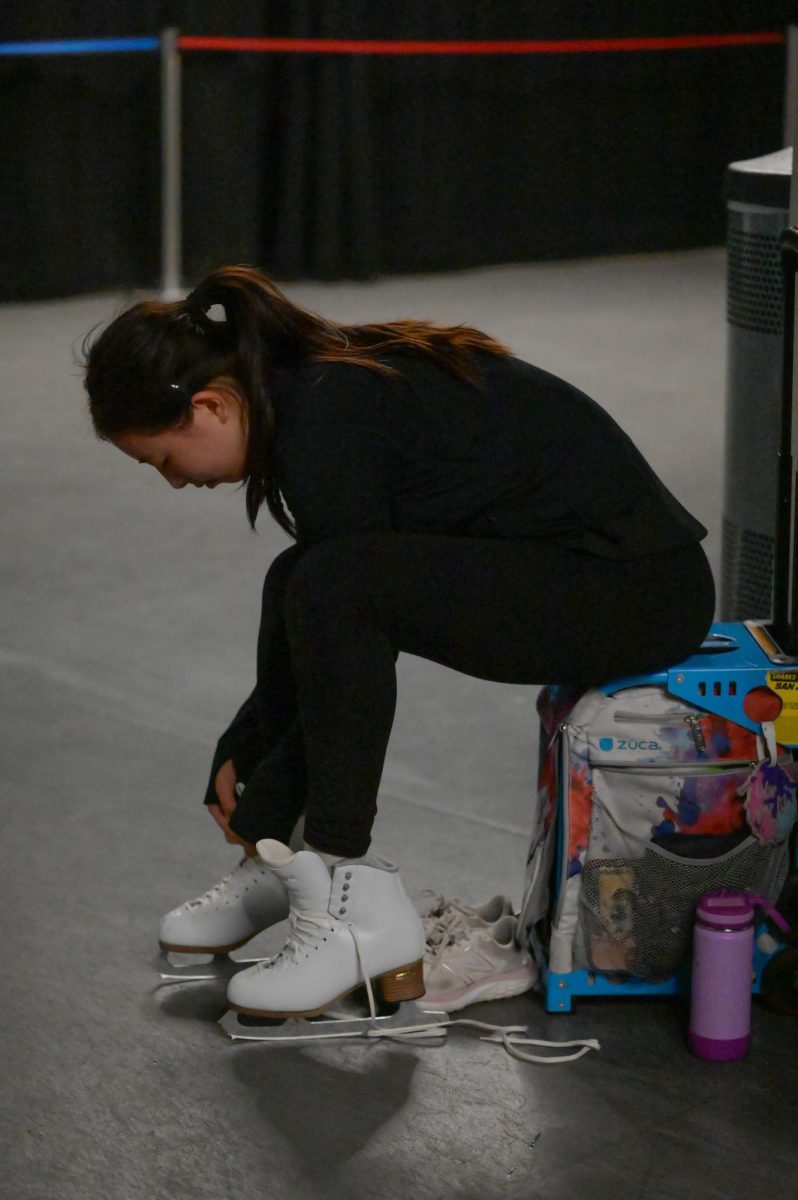 Figure skater Christy Ma (11) laces up her skates before practice. She arrives at the rink at 5 a.m. to train before school.