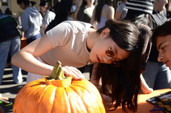 Annie Yu (9) leans over a pumpkin, examining it carefully. The frosh's pumpkin carving ended up in third place.