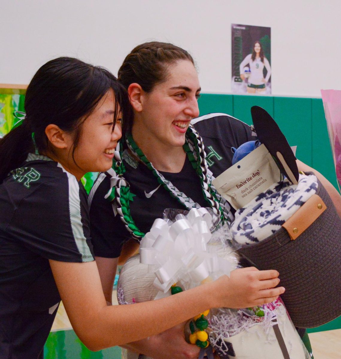 Sophomore Joyce Zhang and senior Emily Mitnick hug and smile for a photo as Emily holds her gift baskets. Before the senior night, the team went to Target to buy gifts like blankets, candy and stuffed animals to put in the gift baskets. 