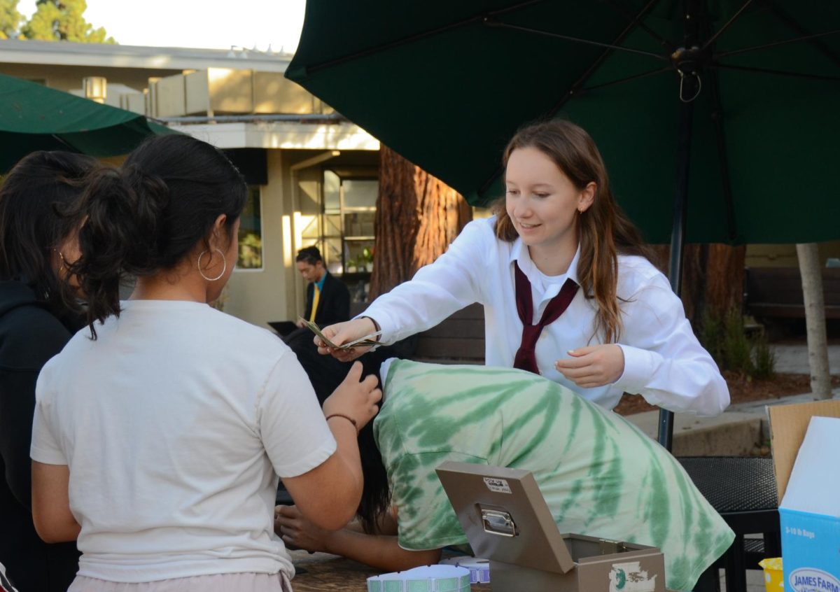 Sophomore Nicole Dean, a member of the ASB Community Service committee, returns money to a student. Members of the committee gave out tickets to students to then buy products from clubs.