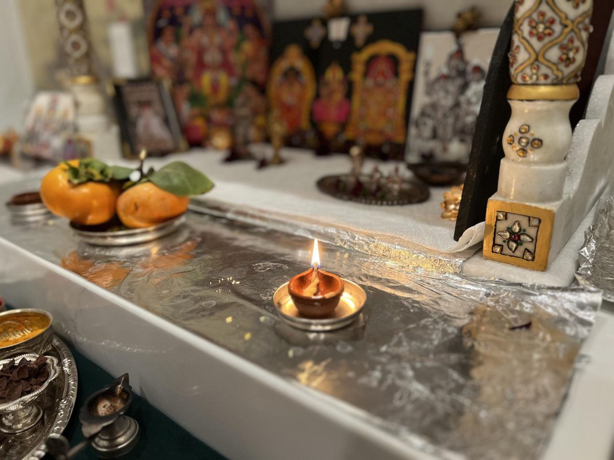 A diya, a clay lamp, sits lit on a traditional Hindu altar. A typical Diwali activity is painting the diyas with different colors and designs.