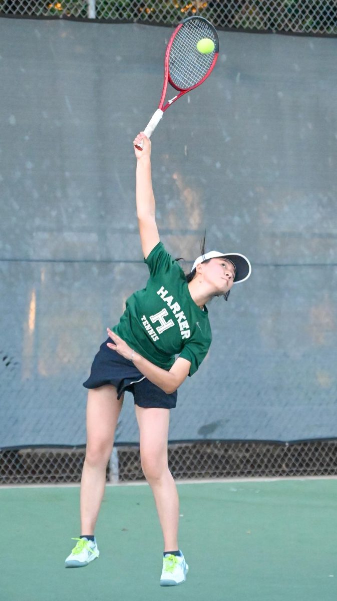 Varsity tennis team member Olivia Guo (12) leaps to serve the ball during a singles match. Finishing the season with  an 11-3 overall record, the team advanced to the CCS semifinal.