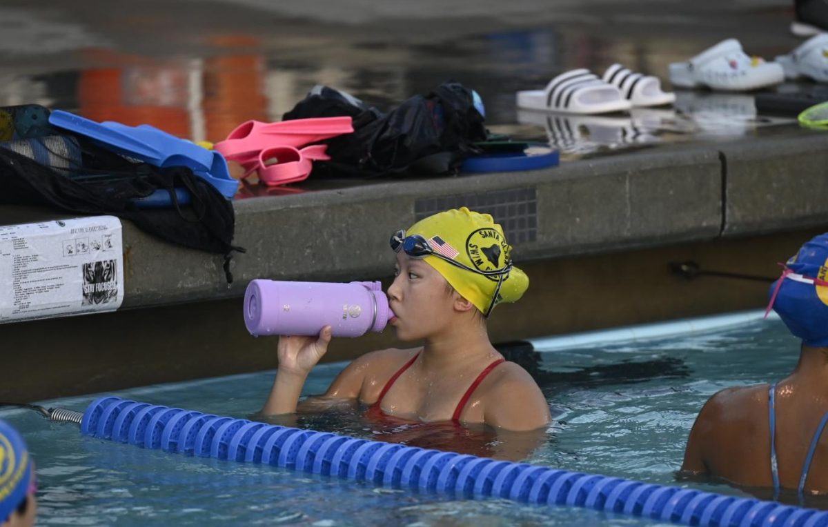 During a break between sets, Eliana takes a sit of water. On double training days, which she has twice a week, Eliana returns to the pool after school for another two and a half hours of practice.