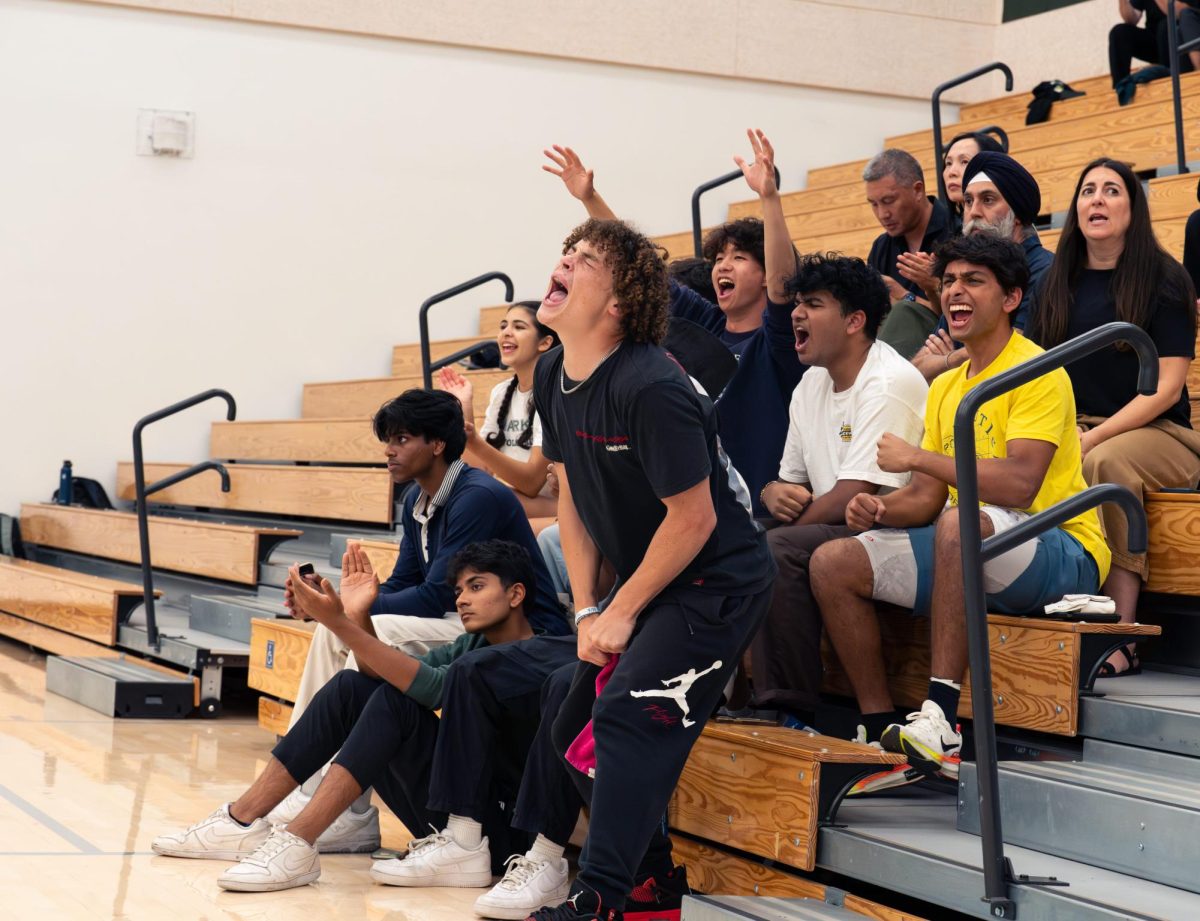 Junior Jackson Powell stands up to cheer during the varsity girls volleyball match. Throughout the season, classmates, friends and family members packed the stands to show their support for the Eagles.