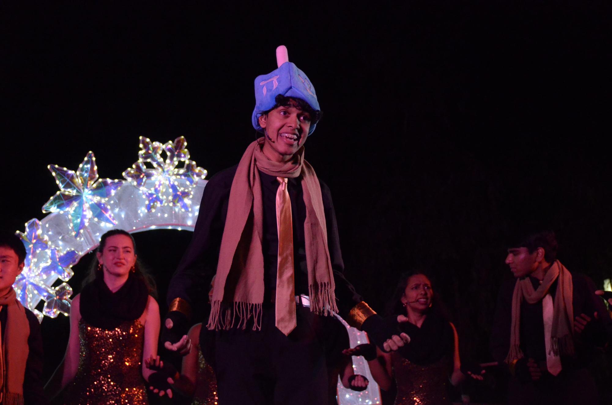 Junior Aditya Ramanathan performs a portion of "Dreidel Dreidel Dreidel" while wearing a hat shaped like a dreidel. A snippet of this tune was interspersed between the song "The 12 Days of Christmas Confusion."