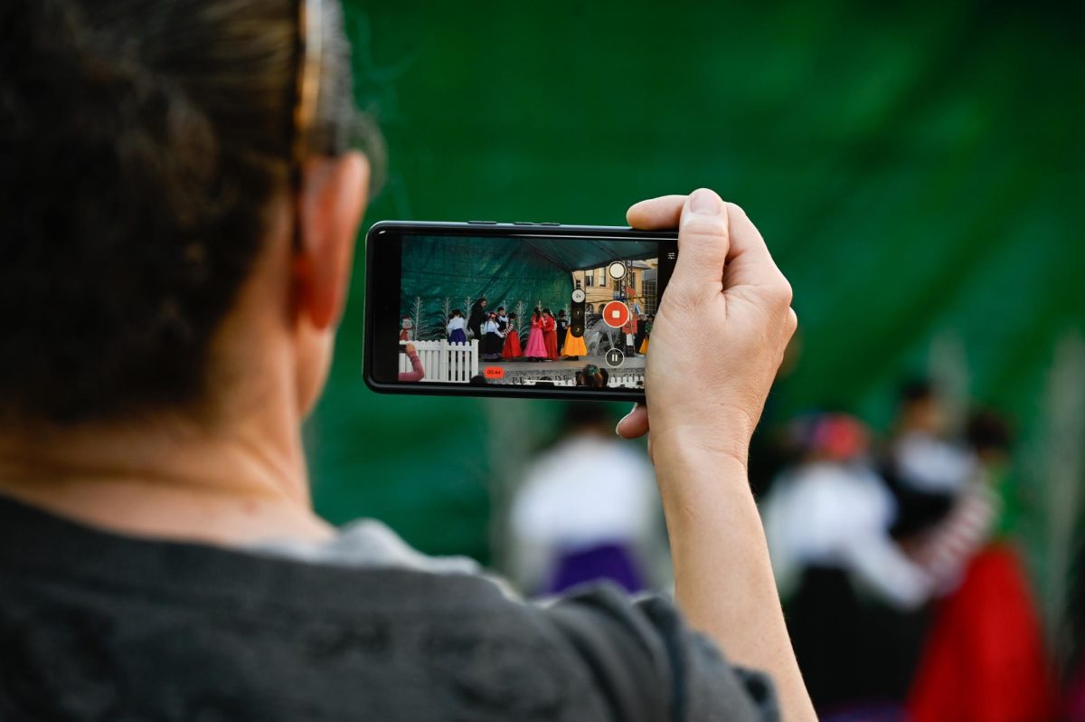 A man records a festive dance performance by Blackford Elementary School. Showcasing local schools, Christmas in the Park aims to infuse all parts of San Jose culture into its celebrations.