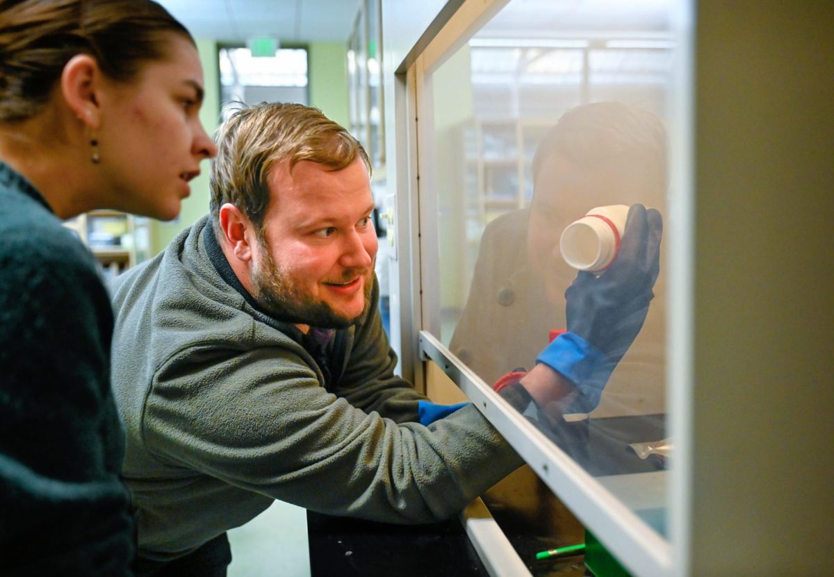 Open lab facilitator Dr. Zane Moore shows junior Emily Bryan a chemical inside the fume hood. Fume hoods are laboratory safety devices that ventilate hazardous fumes or particles.