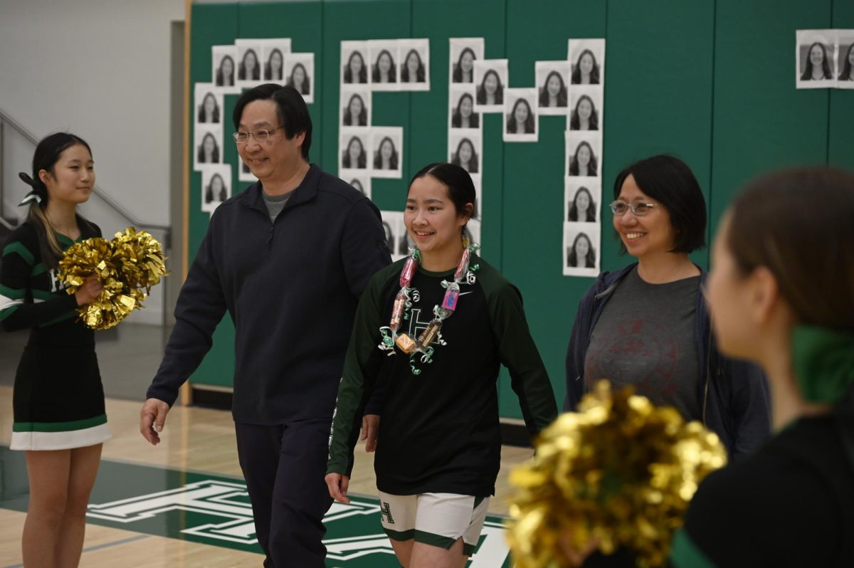 Senior Isabella Lo walks with her parents down an aisle of cheerleaders. Isabella capped off the game with 23 points shooting 60% from deep.