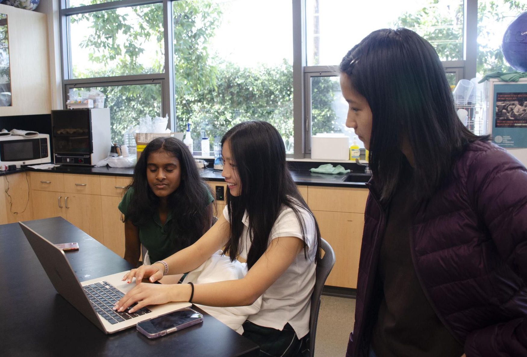 Junior Mendy Mao reads over Abby Eu (8) and Danya Arun's (8) abstract. SRP students worked on developing their abstracts while Research Club speakers assisted them.