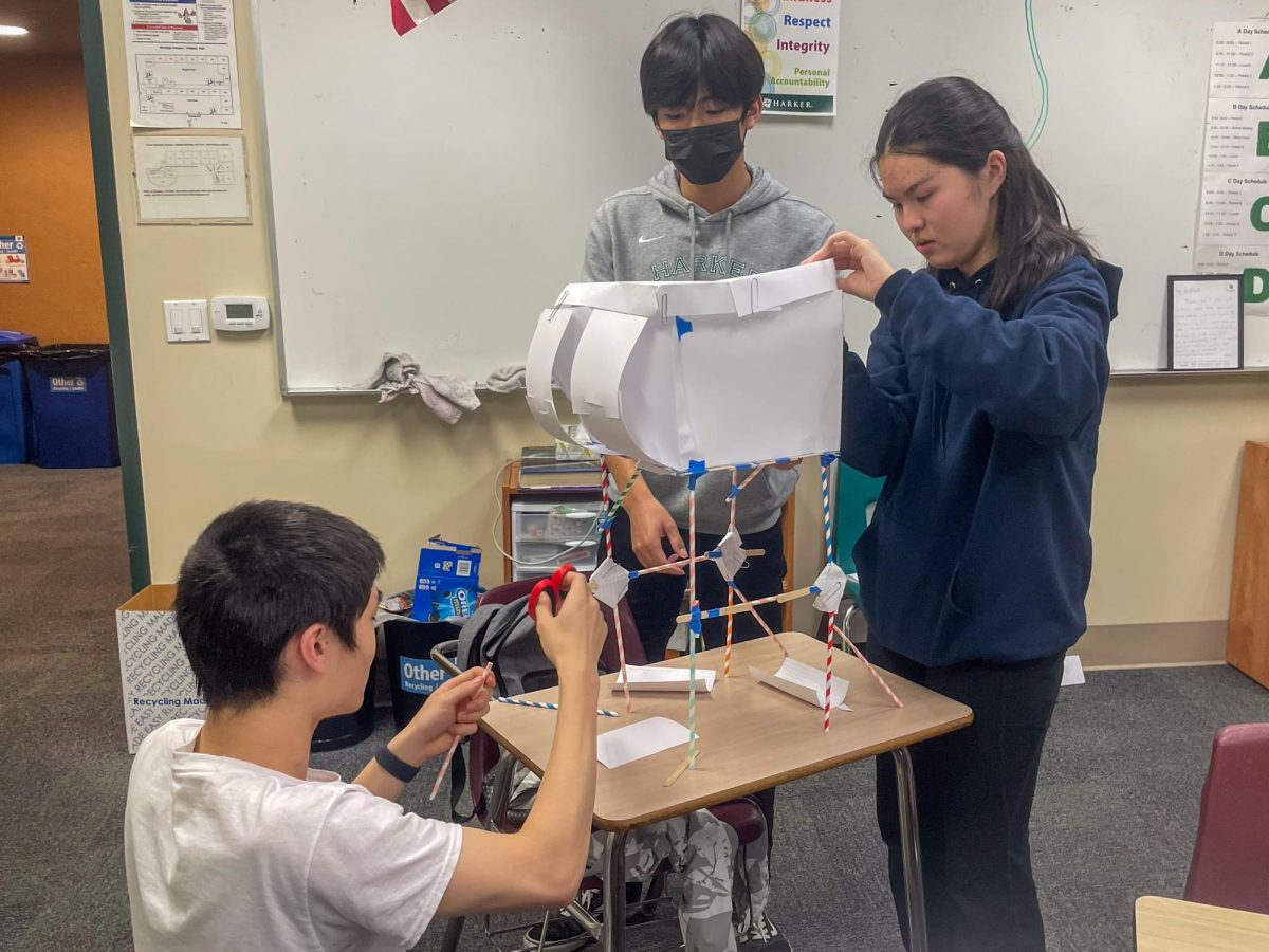 Sophomores Justin Yang, Eric Dong and Kathy Chen put the final touches on their stilted house in the design-build part of the competition. Teams competed to construct the tallest and most wind-resilient model homes using common materials like straws and paper.