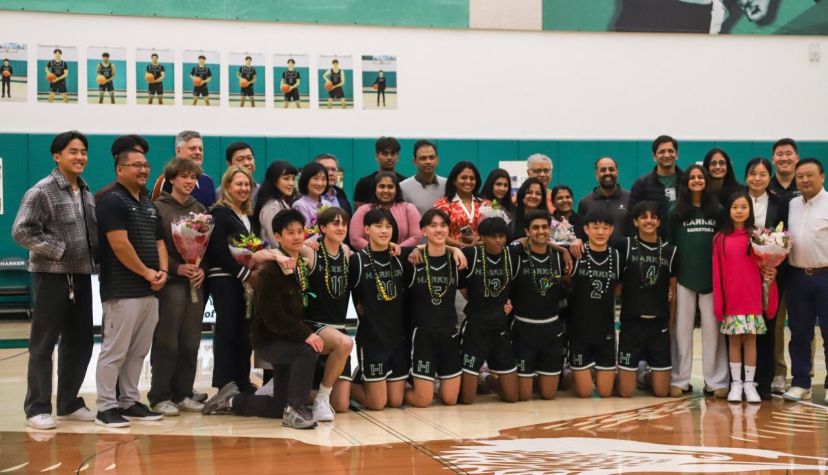 Seniors from the varsity boys basketball smile for a photo with their friends, family and coaches. Prior to their game, the seniors received posters and flowers during the ceremony. 