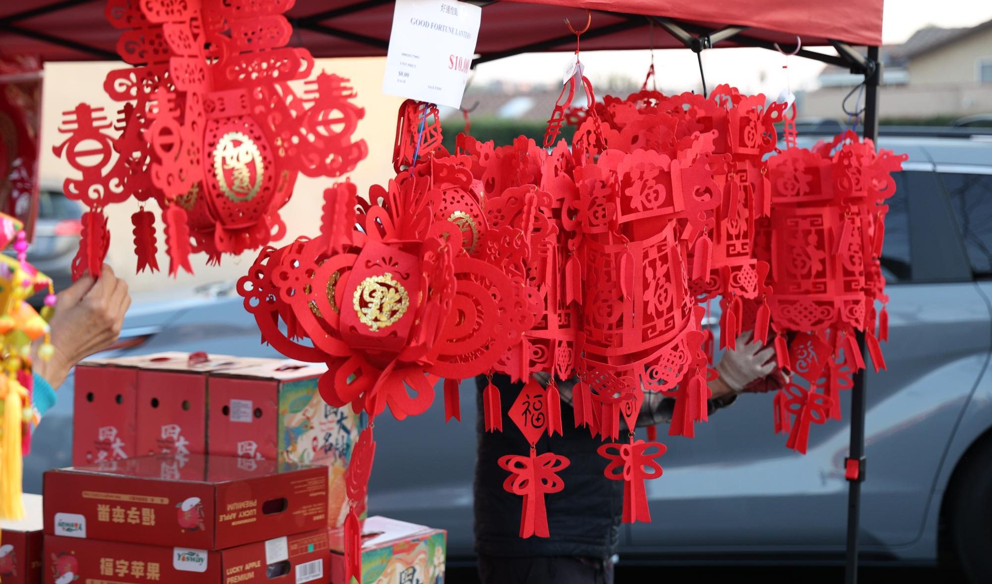 Red lanterns hang from a stall. Emblazoned with the Chinese character for luck, these decorations often line the insides of homes.