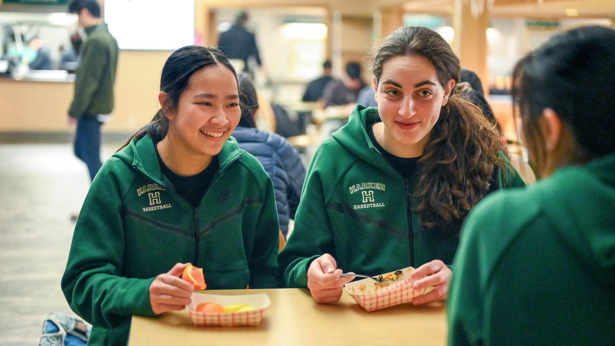 Varsity girls basketball captains Isabella Lo (12) and Emily Mitnick (12) exchange stories with their teammates during lunch. The captain organize frequent team lunches to facilitate team bonding during the season.