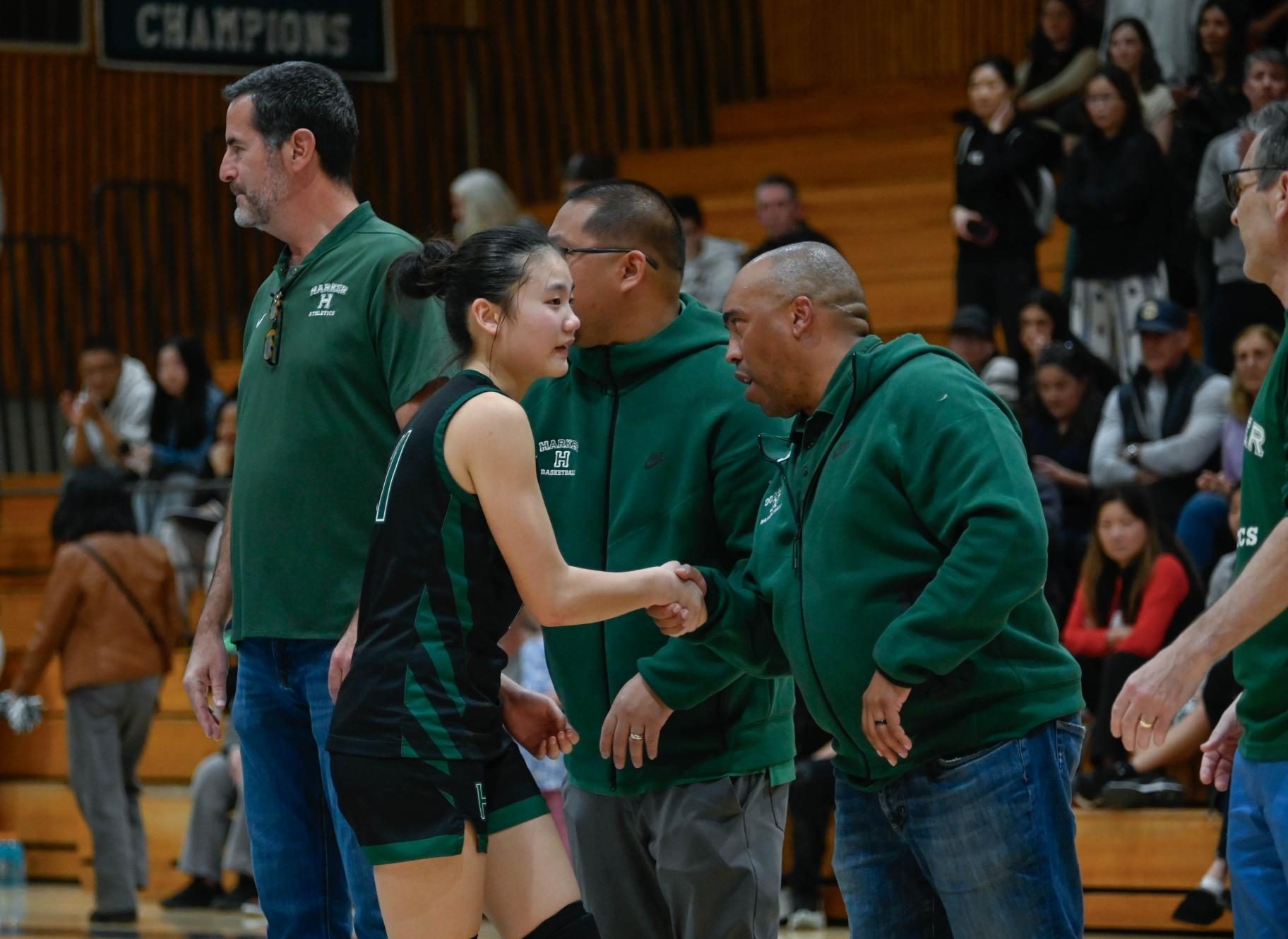 Point guard Jillian Chen (9) shakes hands with Assistant Head of School Ken Allen after the match. Members of both Harker's athletic and administrative staff congratulated the team on their efforts. 