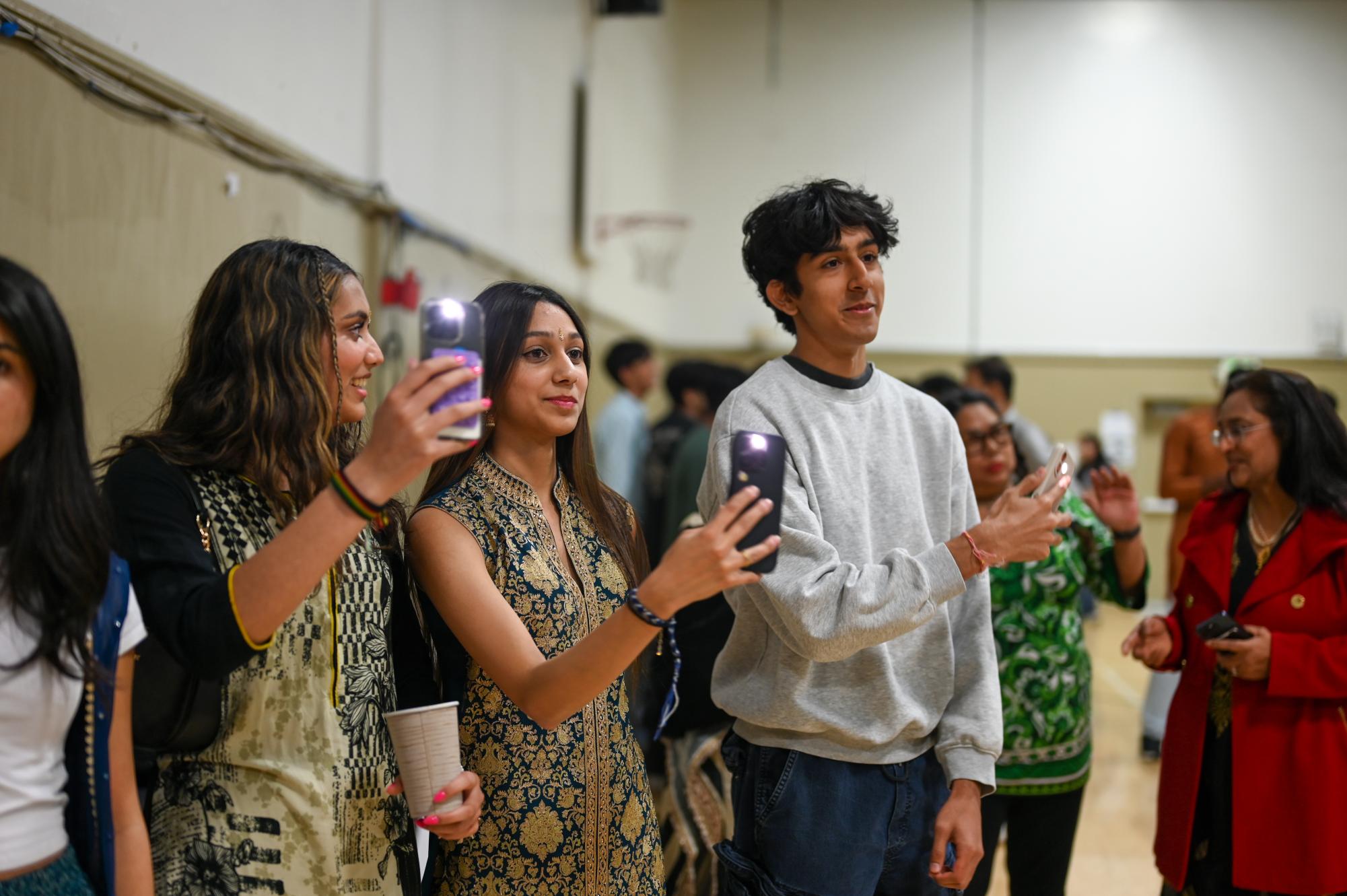 Juniors Angelina Antony and Veeraz Thakkar wave their phones as Dr. Aiyer sings “Chinna Chinna Asai.” Attendees enthusiastically cheered for every performance, creating a vibrant and connected atmosphere.