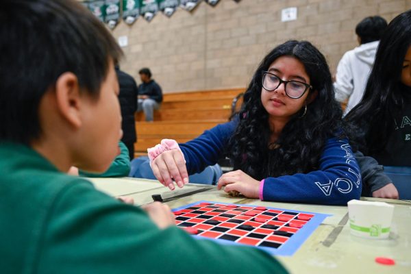 Junior Suhana Bhandare plays a game of checkers with her Eagle Buddy. Students engaged in both indoor activities like card games and coloring, and outdoor games like basketball and wall ball.