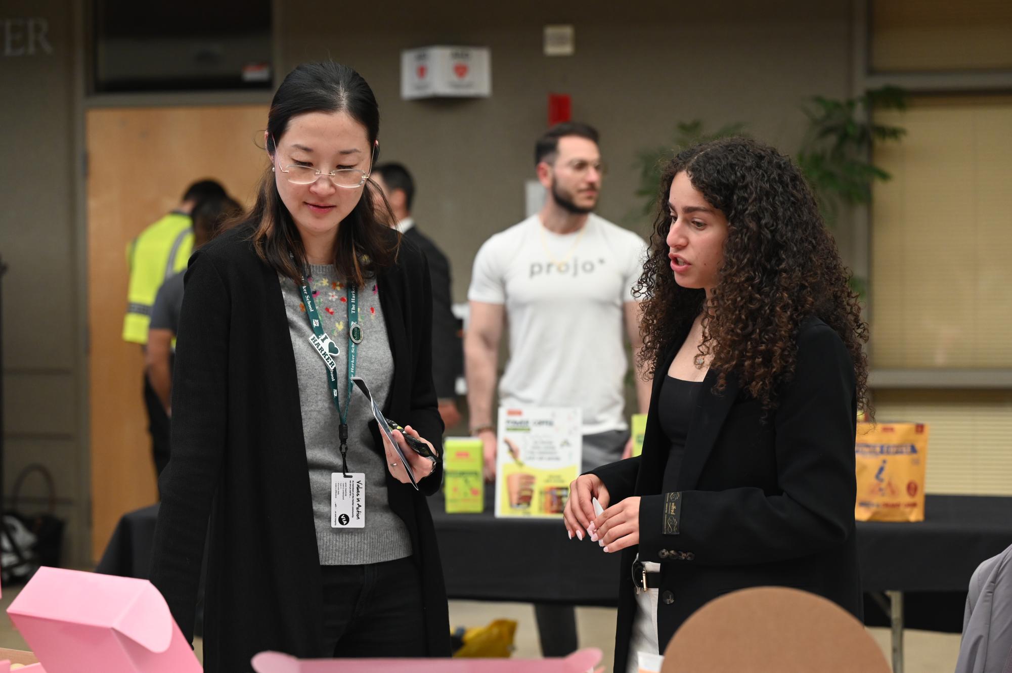Senior Norah Mehanna discusses her business, Curlosophy, with Director of Annual Giving Jun Wang. Curlosophy was one of nine booths that presented their products at BEcon.