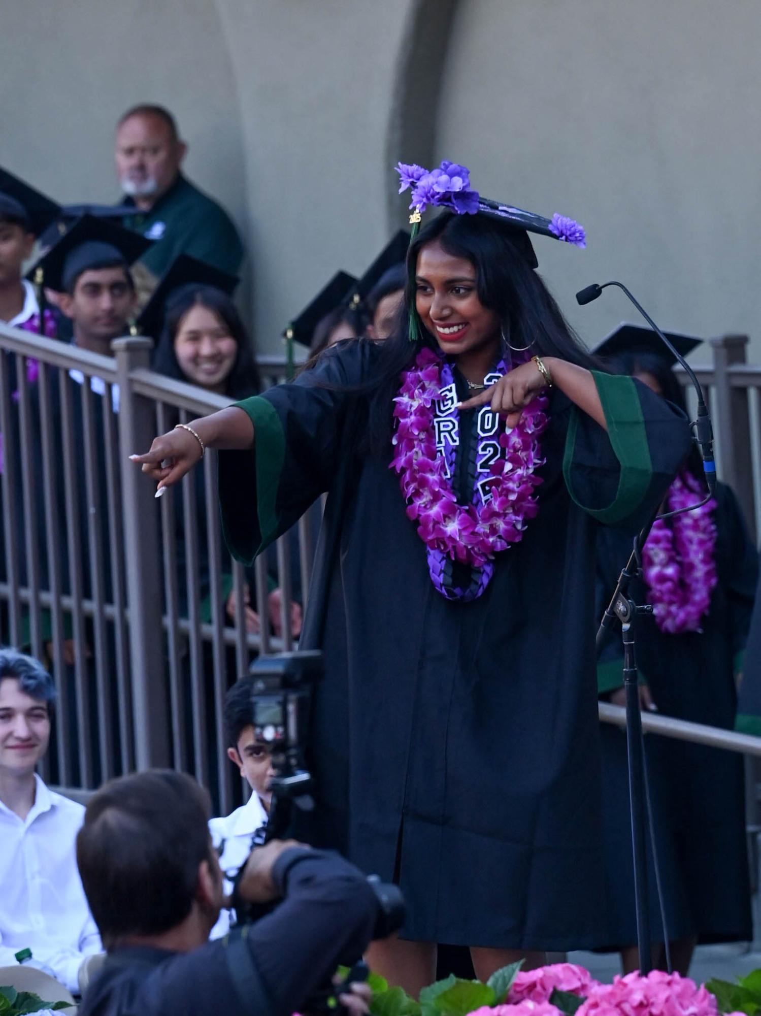 Senior Bhavya Srinivasan strikes a pose in front of the camera before receiving her diploma. After all students collected their diplomas, they flipped their tassels and threw their caps into the air.