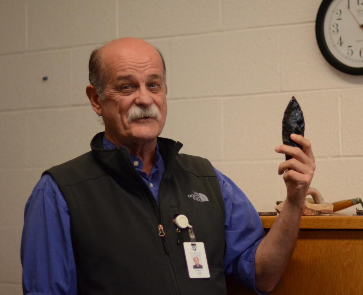 Clifford Hull holds up an ancient artifact, sharing his love for archaeology and the connections it offers to the past. After 47 years of teaching, Hull is retiring at the end of this school year.