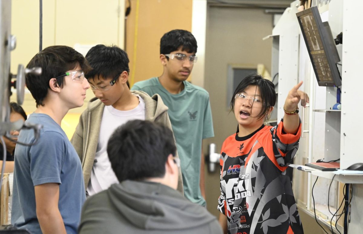 Sophie Yeh (11) instructs students on how to use the Tormach CNC mill. Over the course of the week, the mechanical/machining group learned how to use all the machines, tools and standard components.