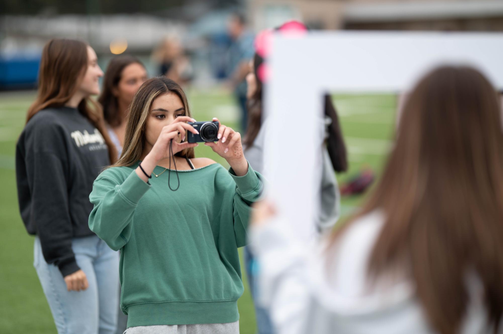Senior Ruhi Banerjee snaps a photo of her classmates on a digital camera. While the sunrise was hidden behind clouds, students watched the sky gradually brighten to signify the symbolic new beginning.