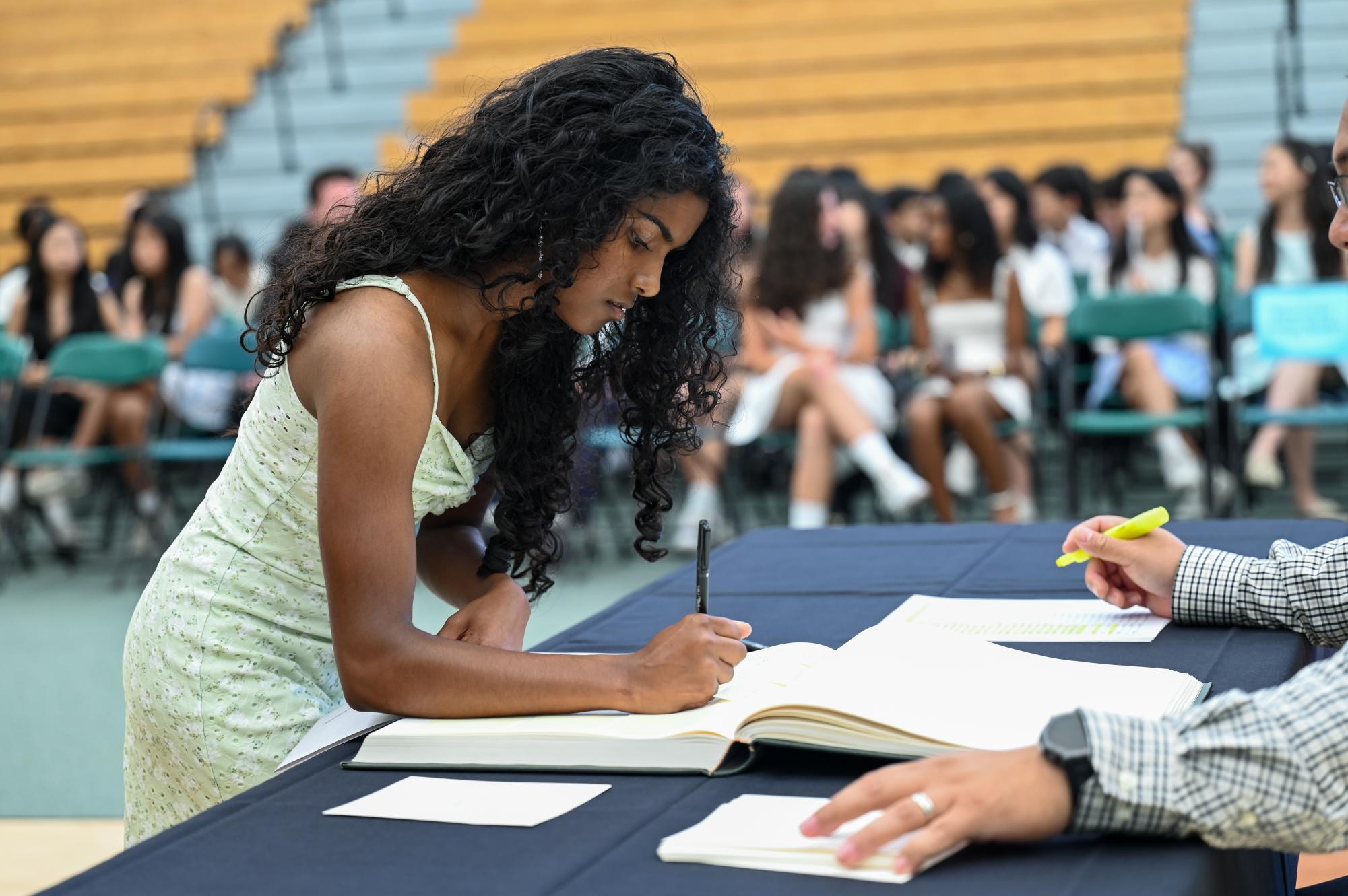 Frosh Nila Gunaratnam signs the Matriculation Book, pledging to uphold the Matriculation Oath. Frosh stayed behind in the Zhang Gymnasium after the ceremony for a more intimate signing ceremony.