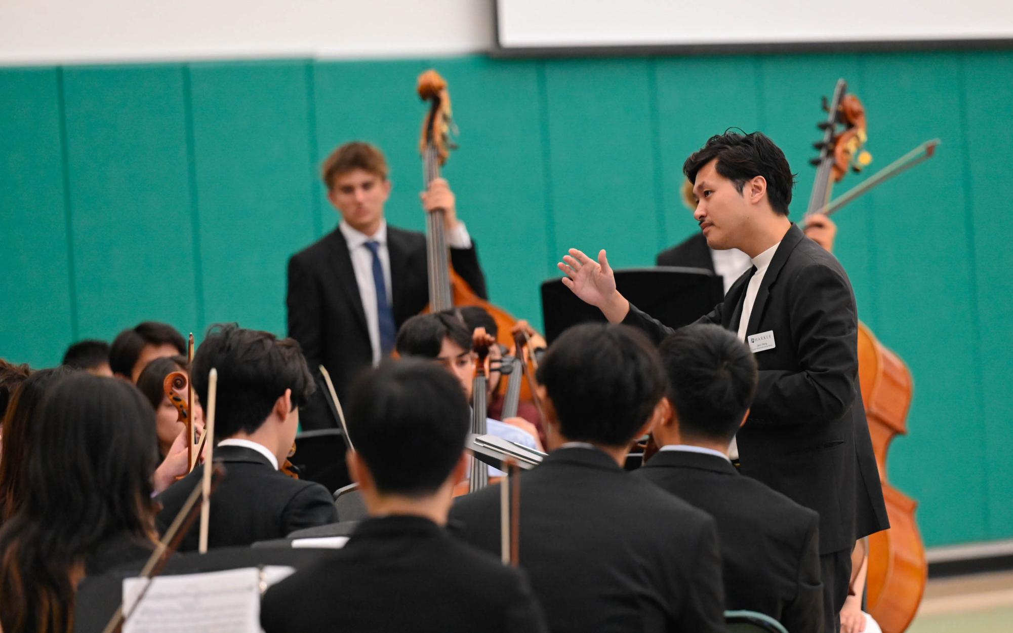 Instrumental music teacher Jaco Wong leads the Harker Chamber Orchestra. In between speeches, they played pieces "Intermezzo" and "Toreador" From Carmen Suite by Georges Bizet.