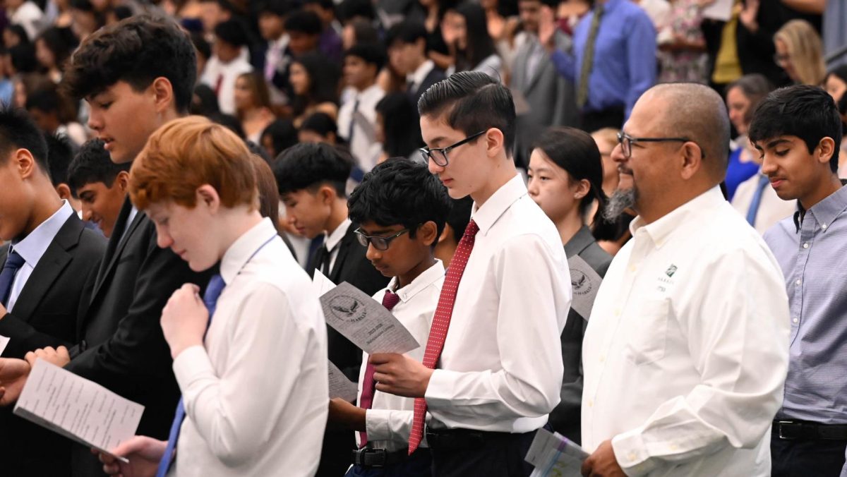 Frosh students and advisers stand as they read the Matriculation Oath. Afterwards, the student body viewed videos of skits about Harker student life.