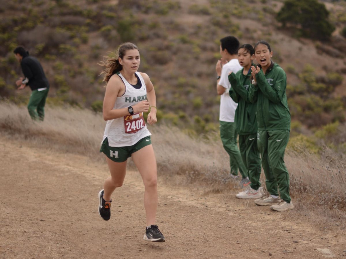 Senior varsity girls runner Emily Bryan runs her final mile after passing Cardiac Hill, cheered on by teammates Sophie Shen (9) and Hannah Tay (9). Emily placed 4th in the senior girls race with a time of 21:39.6.