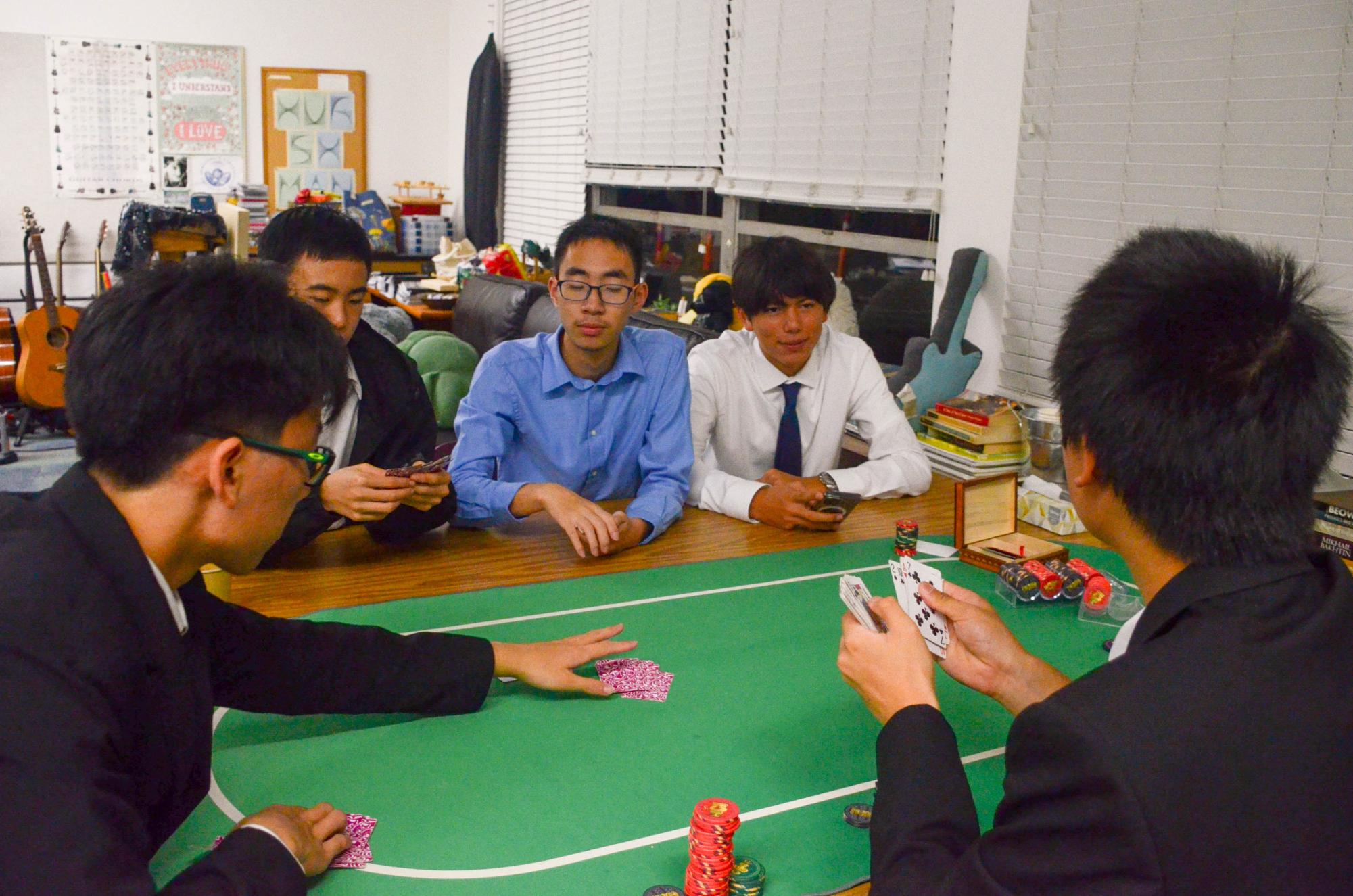 Junior Haofang Zhu plays a game of poker in Mr. Hurshman's room. Students relaxed outside of the gym to take a break from dancing and engage in Vegas-themed festivities and games.