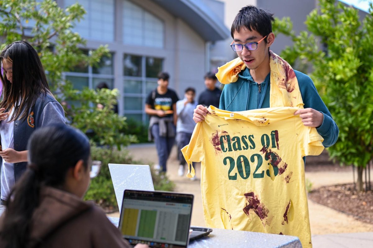 Junior Haofang Zhu holds up a blood-stained shirt while checking in with HSLT during lunch. The class of 2027 passed out decorated shirts to follow their "zombie" theme.