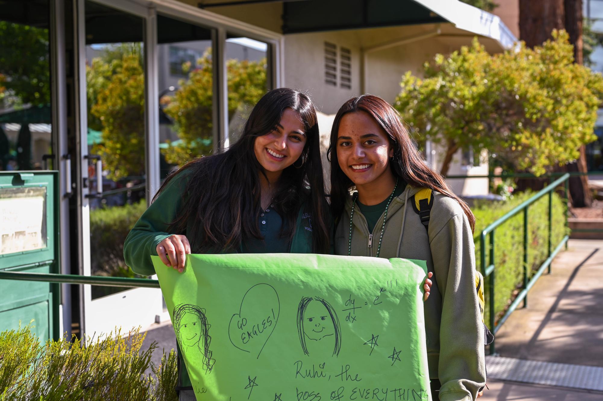 Seniors Minal Jalil and Janam Chahal hold up a green poster while decked out in the senior class color. Fall Spirit Week will continue on Wednesday with a wilderness-themed dress-up and a series of “Minute to Win It” games during lunch.