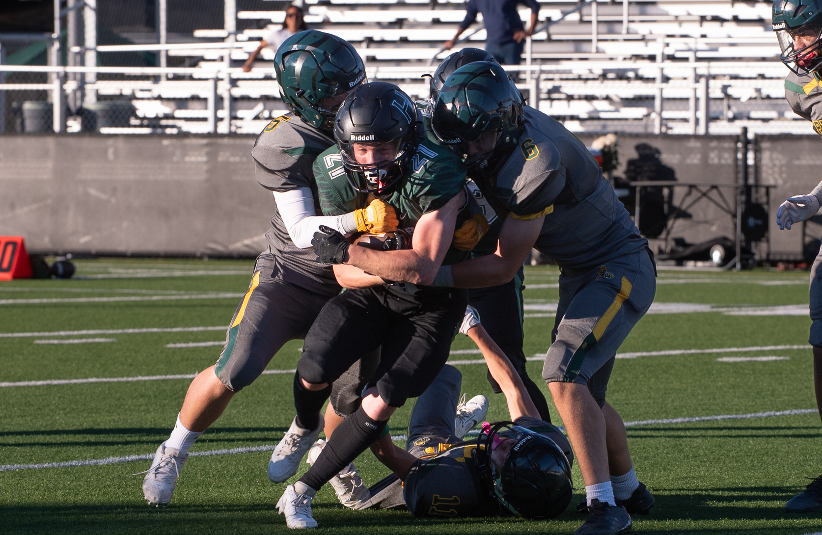 Running back Jackson Powell (12) clutches the ball as three defenders attempt to bring him down. Jackson scored five touchdowns in the Eagle's win.