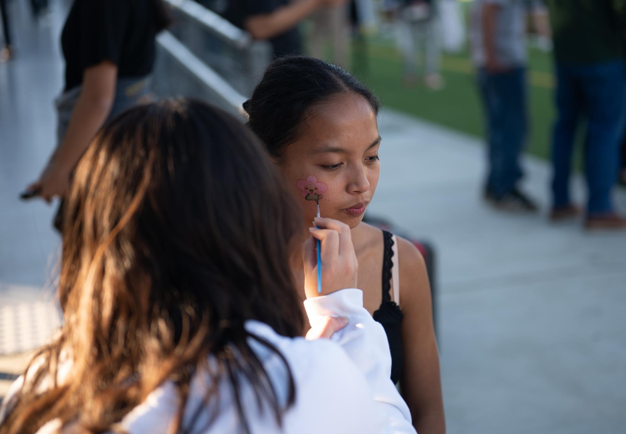 Junior Ava Alvarez gets her face painted before the game. Campus Leadership Coalition organized numerous pregame activities, from a barbeque cookout to face painting