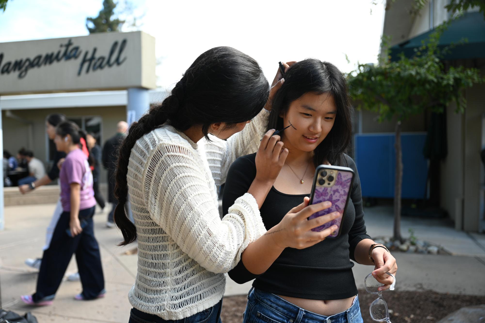Junior Riya Samuel paints a scar on junior Lemeng Kong's face. The junior theme was zombies, so they painted scars and wounds on their face.