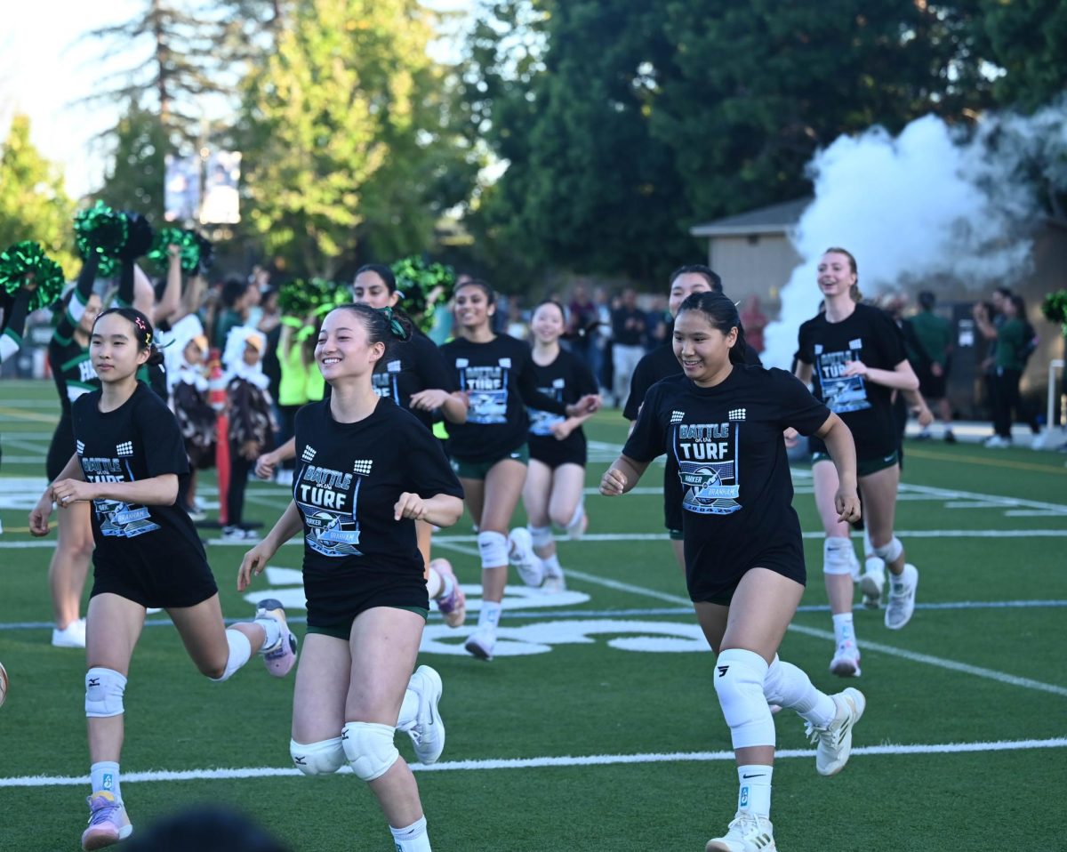 The girls varsity volleyball team runs out flanked by the cheerleaders. Smoke billowed behind them and the crowd went wild as they exited from the locker rooms a few minutes before the starting whistle.