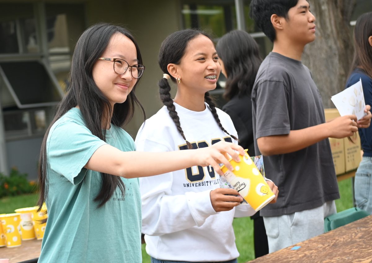 Class council member Kallie Wang (12) smiles and hands boba to another student. Students were able to choose from different flavor options when they signed up via the google form.