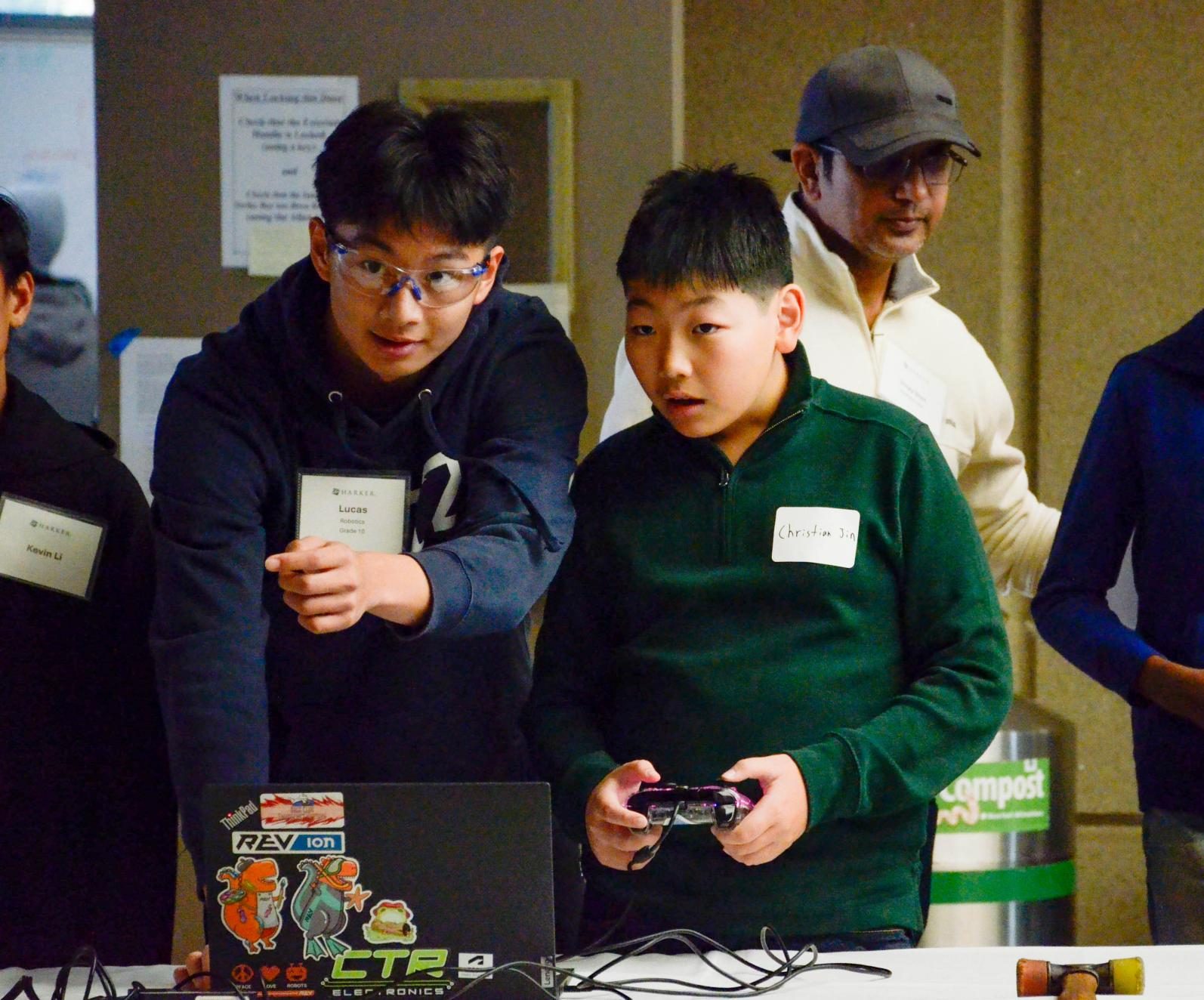 Sophomore Lucas Huang teaches a prospective student how to control a Harker robotics robot. Robotics featured a special booth with a live demo of their competition robot in action.