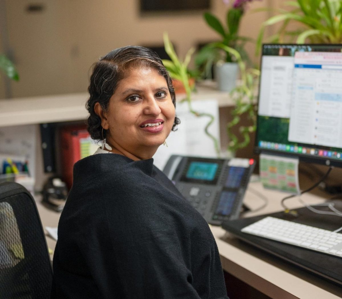 Raaj smiles at her desk in the front office. “In my communication with students, I try to be more compassionate because I understand when they are going through things,” Raaj said.