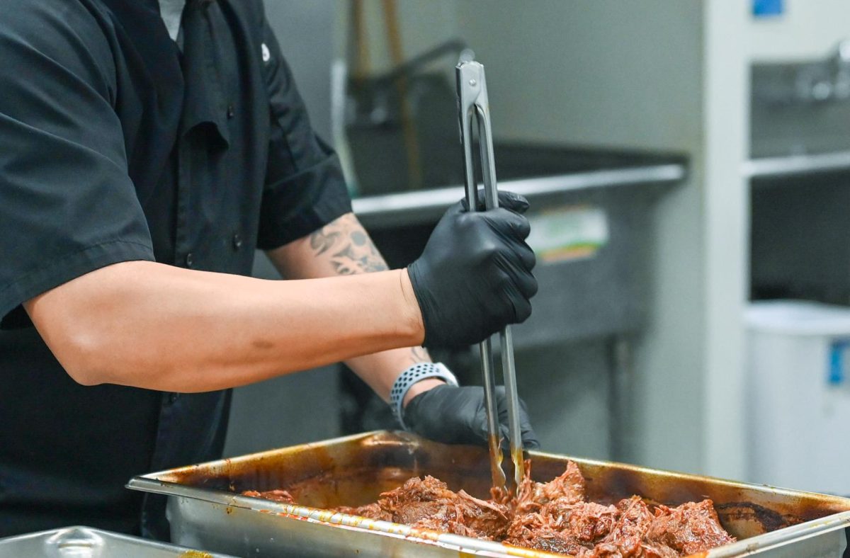 Cook Jimmy Abellanosa uses tongues to break apart birria meat. Abellanosa arrives to the upper school campus at 7:30 a.m. every morning. 