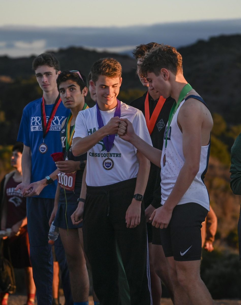 Varsity cross country runner Axel Szolusha (11) congratulates an opponent. He placed sixth during WBAL Finals and ran a personal best of 15:59.2 this season.